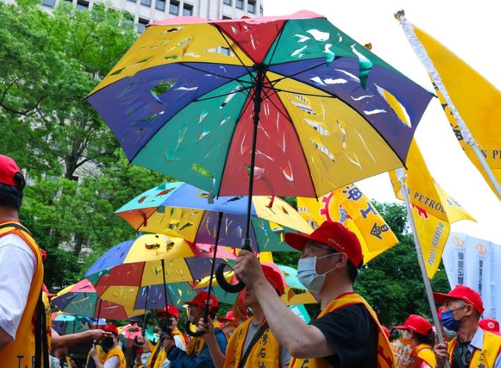 五一行動聯盟「勞工大遊行」，參與民眾高舉破洞的雨傘，象徵退休制度千瘡百孔。圖/中央社