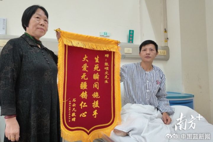 11月11日,石先生在住院病房展示準備好的錦旗,上面寫著「生死瞬間施援手 大愛無疆鑄仁心」。圖/取自《南方日報》