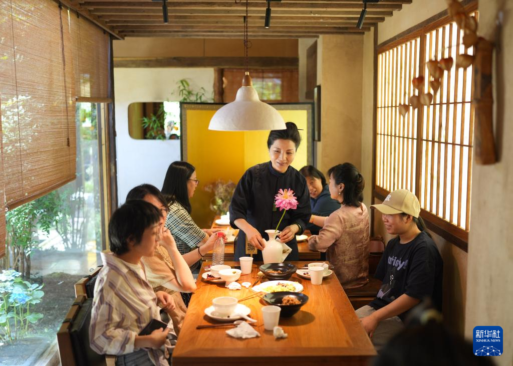 素食餐廳主理人王芳（中）和用餐的客人交流。圖/取自新華網