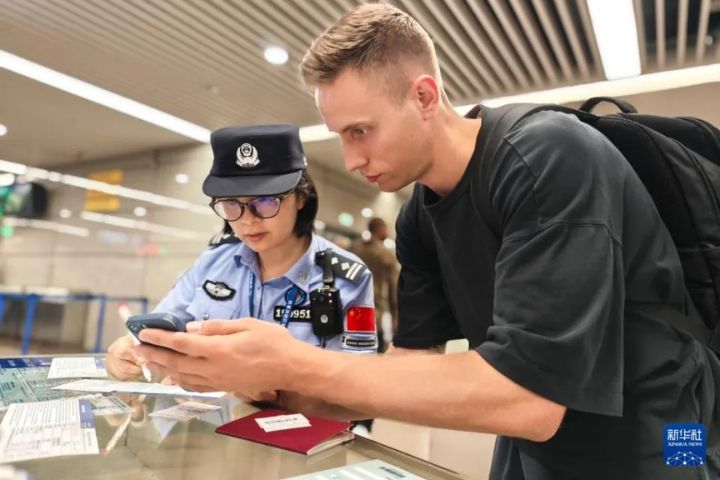 7月18日，上海移民管理警察協助旅客（右）填寫入境表格。圖/取自新華社