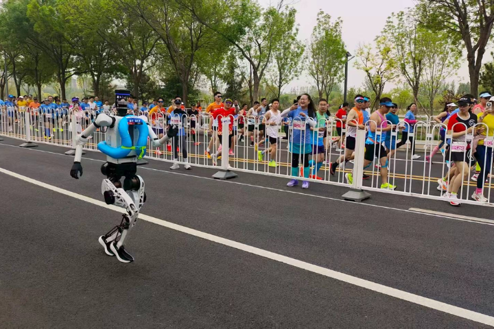 4月19日，半程馬拉松暨人形機器人半程馬拉北京亦莊舉行，圖為人類跑者在比賽過程中停下腳步，記錄機器人飛奔身影。圖／李嘉薇 攝