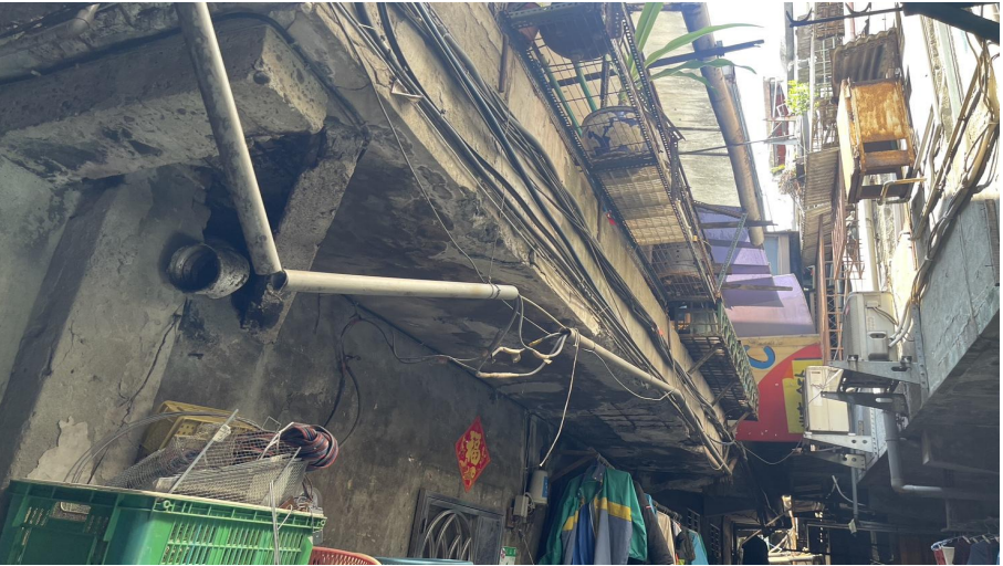 狹窄巷弄上方管線、電纜盤根交錯，牆面剝落、樑柱裸露，住戶只能將衣物晾在陰暗巷道間，公共安全與居住品質長年堪憂，正是政府完成拓寬馬路的公共工程後、忽略遷建戶後續居住權的縮影。圖／台北遷建提供