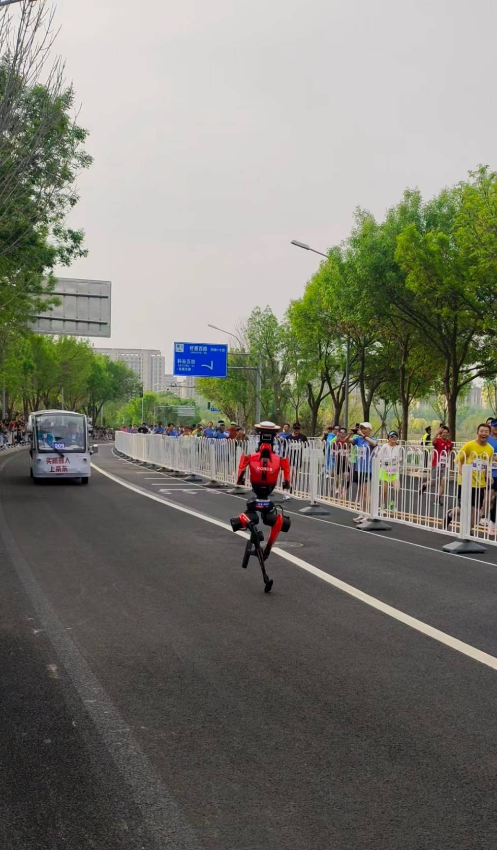 4月19日，半程馬拉松暨人形機器人半程馬拉北京亦莊舉行，圖為人類跑者在比賽過程中停下腳步，記錄機器人飛奔身影。圖／李嘉薇 攝