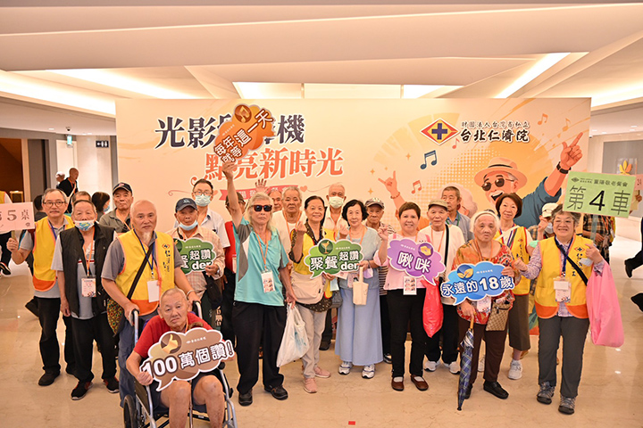 長者們手持趣味標語牌,在活動主視覺背板前開心合影。 圖/台北仁濟院 提供