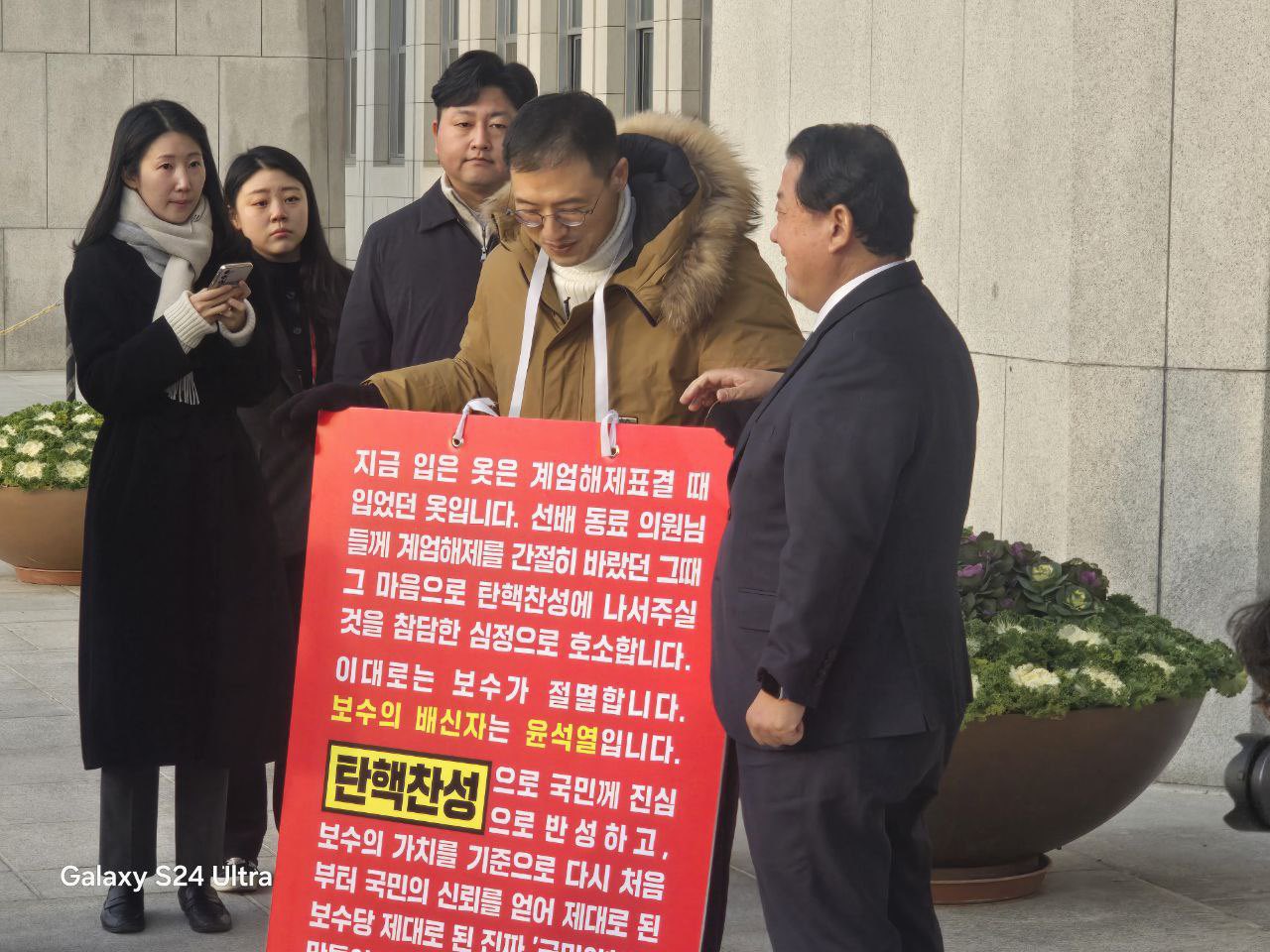 南韓國會今（14日）將二次彈劾總統尹錫悅，圖為執政黨國民力量黨議員金尚旭，在國會面前舉行一人抗議，呼籲執政黨彈劾尹錫悅，最後也把黨魁韓東勳帶上。圖／取自@areainarea X