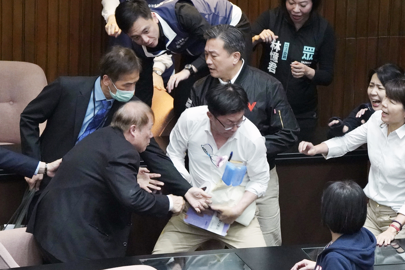 民進黨立委郭國文（前中白衣者）突然暴走，搶走秘書長周萬來（前左）懷中資料後一路跑出議場，現場藍委怒吼「郭國文攻擊秘書長」。圖/中央社