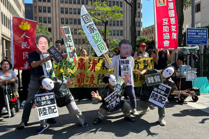 民團今天（3日）在陸委會大樓外抗議陸配除籍專案，一人戴著總統賴清德面具，高舉「打掉雜質」錘子，另一人則戴著陸委會副主委梁文傑的面具，脖子上掛著「除籍劊子手」牌子。圖/取自Tifa台灣國際家庭互助協會粉絲團 