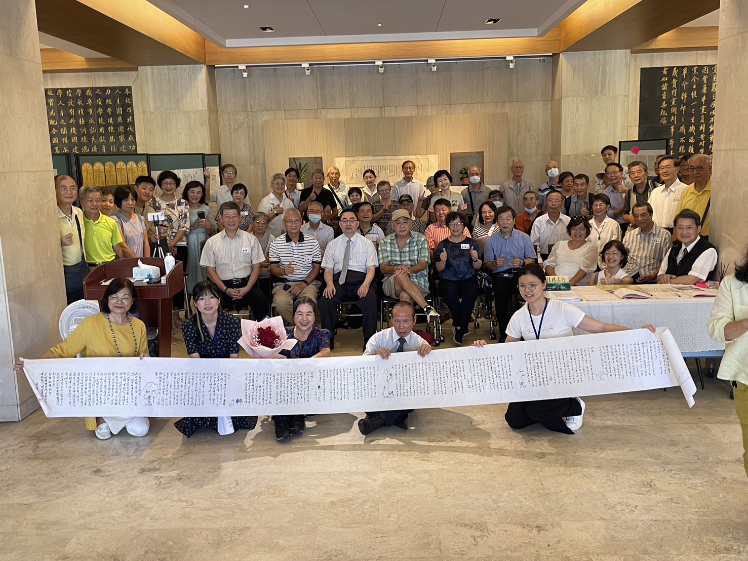 政大「毛筆情書」個展的與會貴賓在4.5公尺長的情書背後大合照。圖／周祝瑛提供
