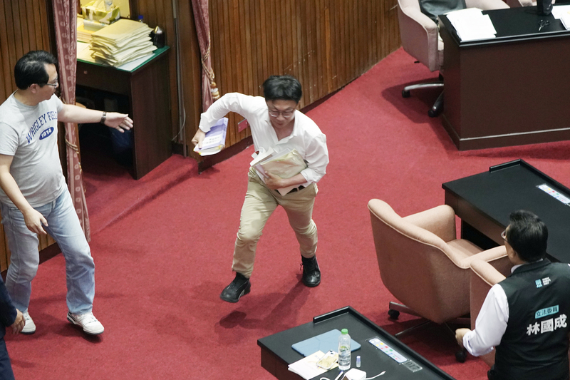民進黨立委郭國文（中）在議場中搶走立院秘書長周萬來手中提案資料，隨即轉身跑開。圖/中央社