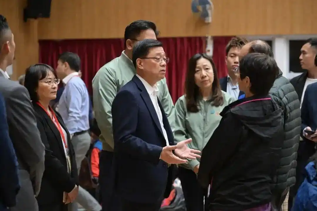 港府特首李家超(中)前往宏福苑探望受災居民。不過可預見的是,事件後港府恐也將遭檢討。圖/取自大灣區之聲