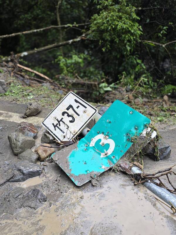 新竹縣北埔鄉通往苗栗縣南庄鄉的竹37-1線道路4日受雨勢影響,落石崩塌、路面泥濘,路旁標示牌毀損傾倒。圖/北埔鄉公所提供、中央社
