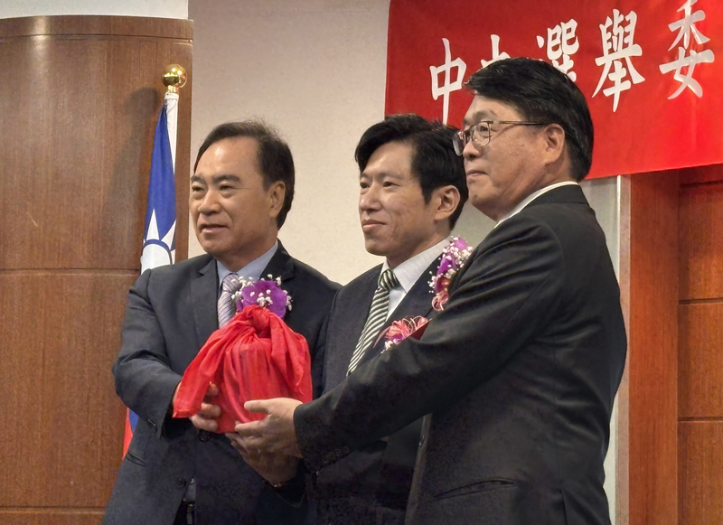 27日在行政院秘書長張惇涵（中）的監交下，代理主委吳容輝（左）、新任主委游盈隆（右）完成交接。圖/中央社