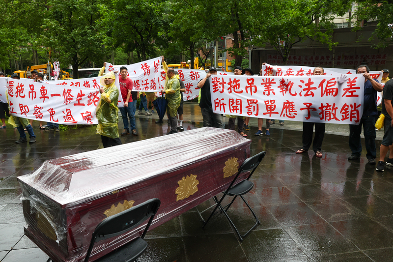 拖吊車業者3日到交通部外集結，抗議現行過磅規定不合理，常出勤過磅就挨罰，與會者將棺材放至交通部前抗議，拉起白布條表達訴求。圖/記者黃楚甯攝