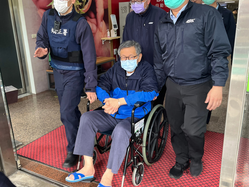民眾黨前主席柯文哲（前中）2日在衛生福利部台北醫院進行輸尿管鏡手術，取出結石後住院觀察。柯文哲3日下午坐著輪椅出院，在台北看守所人員戒護下離開醫院。圖／中央社