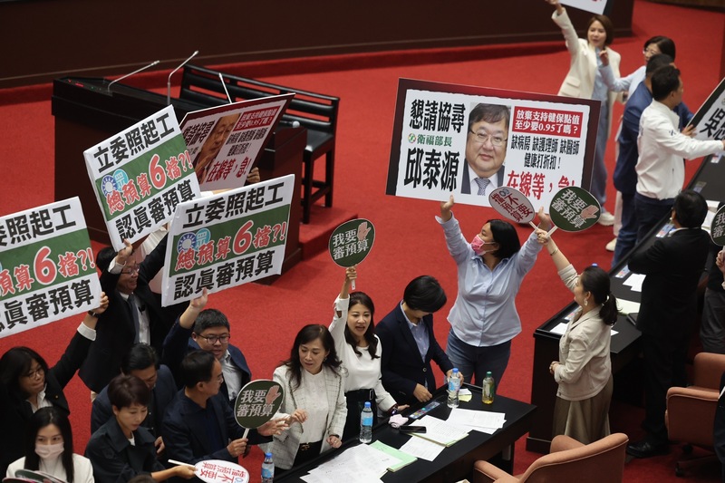 明年度總預算案因行政院未編足禁伐補償等預算而卡關，立法院長韓國瑜5日晚間再召集朝野協商後重新召開院會，民進黨立院黨團提案付委仍遭否決，藍綠立委在場中各自高舉標語表達意見。圖／中央社