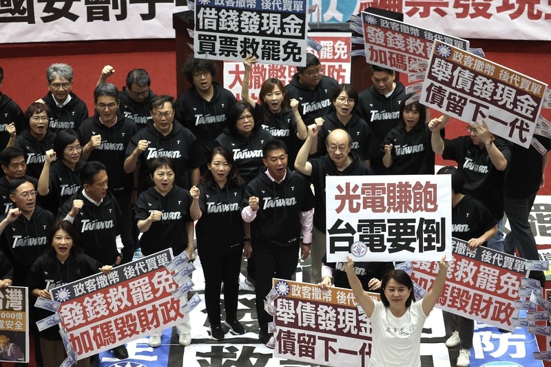 立法院會11日經表決三讀通過國民黨團所提的「因應國際情勢強化經濟社會及民生國安韌性特別條例」，明定將普發現金。三讀後，朝野立委各自在議場內舉牌表達不同立場。圖/中央社
