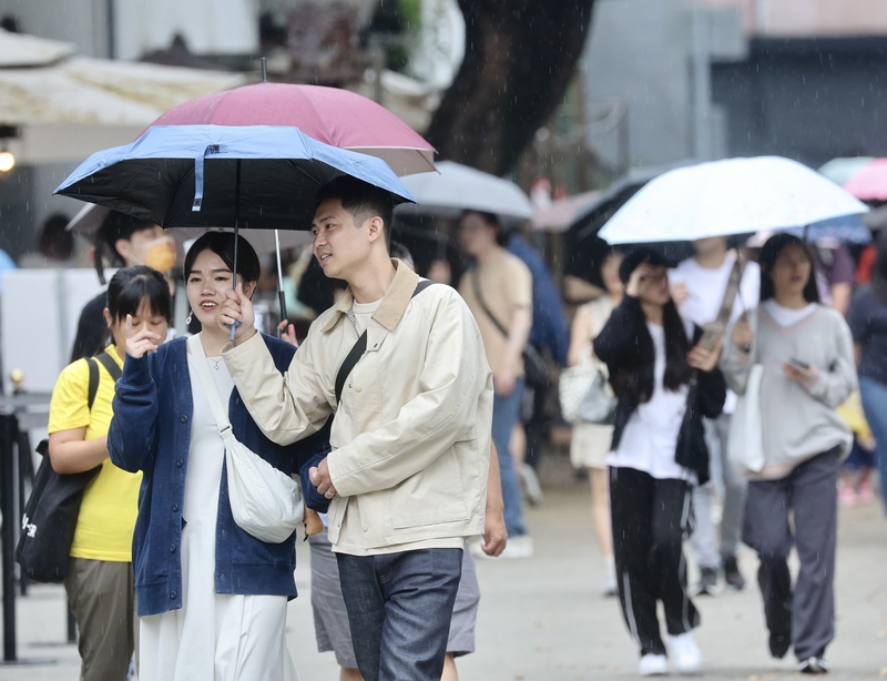 氣象署表示，台灣地區過去百年來溫度上升約攝氏1.5度，年總降雨變化不大，但每年降雨日數減少、短時間強降雨增加。圖為近日天氣不穩定，民眾撐傘遮雨。圖/中央社