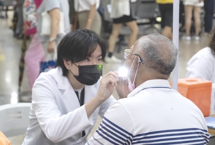 高醫中和醫院25日舉行癌症篩檢活動，圖為醫師為民眾檢查口腔。圖／高醫提供