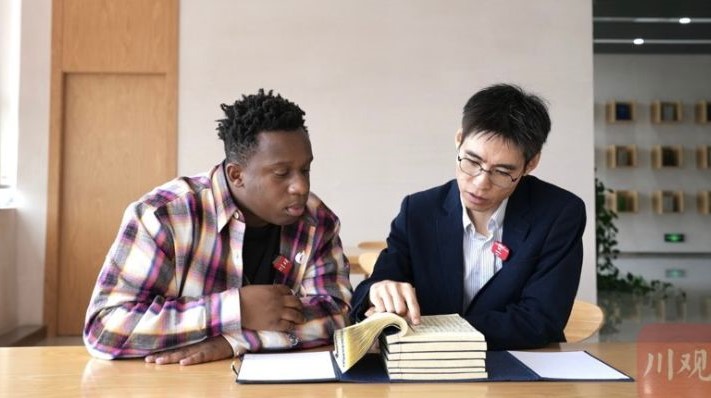 網紅張文(左)在成都大學圖書館內,翻查自己和家人的生活地蒲江縣的縣誌。圖/取自《川觀新聞》
