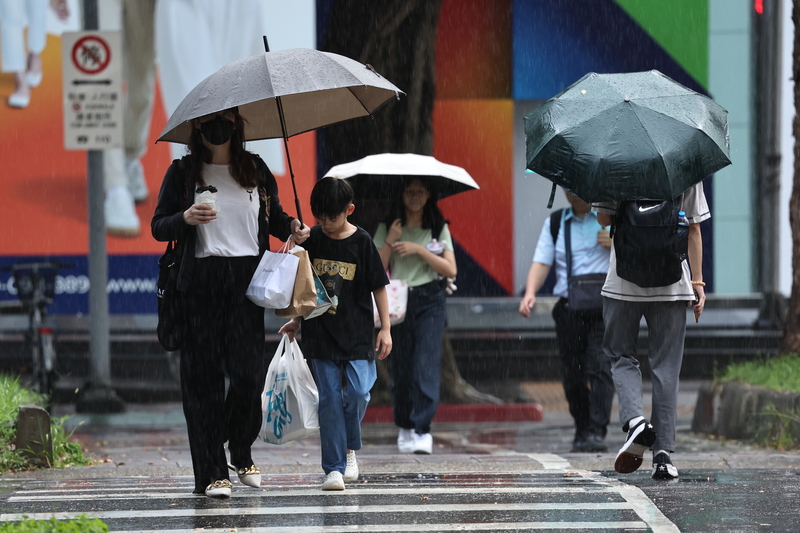 今天午後西半部地區及各地山區有局部短暫雷陣雨，圖為松山區街頭民眾撐起傘走過馬路。中央社