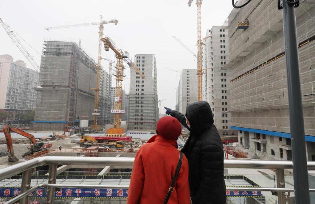 兩位上海市民在彭浦新村地鐵站出站天橋上觀看一建設工地。圖/取自新華社