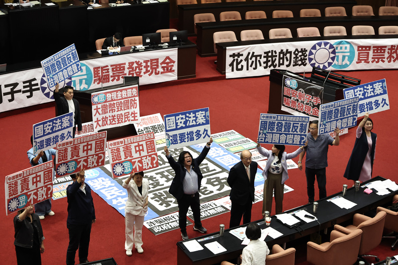 立法院11日上午舉行第11屆第3會期第20次會議，國民黨團希望能拚普發現金三讀通過，但民進黨團於議場高舉看板表達立場，質疑在野黨「發現金救罷免」。圖/中央社