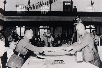 1945年9月9日上午9時，中國戰區日軍投降簽字儀式在南京舉行，在華日軍總參謀長小林淺三郎（右）向同盟國中國戰區中國陸軍總司令何應欽將軍（左）呈遞降書。圖/取自中正紀念堂官網