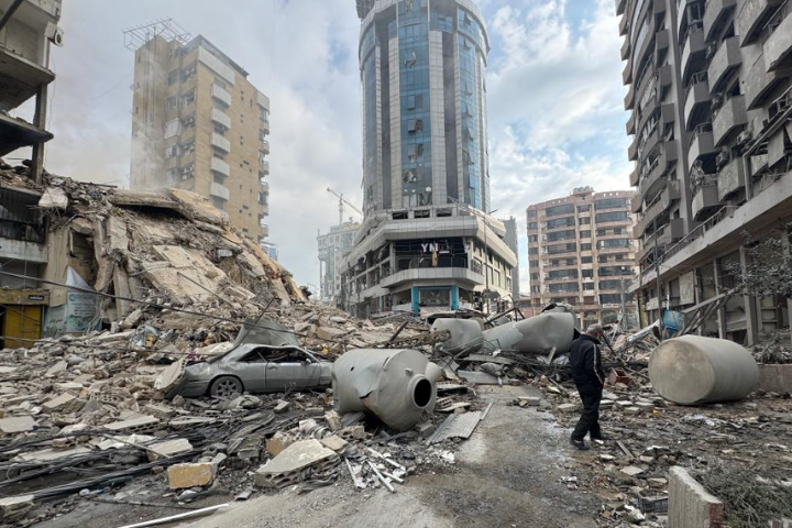 一名男子7日行走在貝魯特南郊被以色列襲擊摧毀的建築廢墟旁。圖/取自新華社