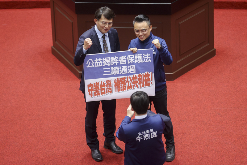 立法院會27日三讀通過公益揭弊者保護法，保障公部門、國營事業及受政府控制的事業、團體或機構揭弊者的權益。國民黨立委洪孟楷（後右）與民眾黨立委黃國昌（後左）開心持標語合影，慶祝法案通過。圖／中央社