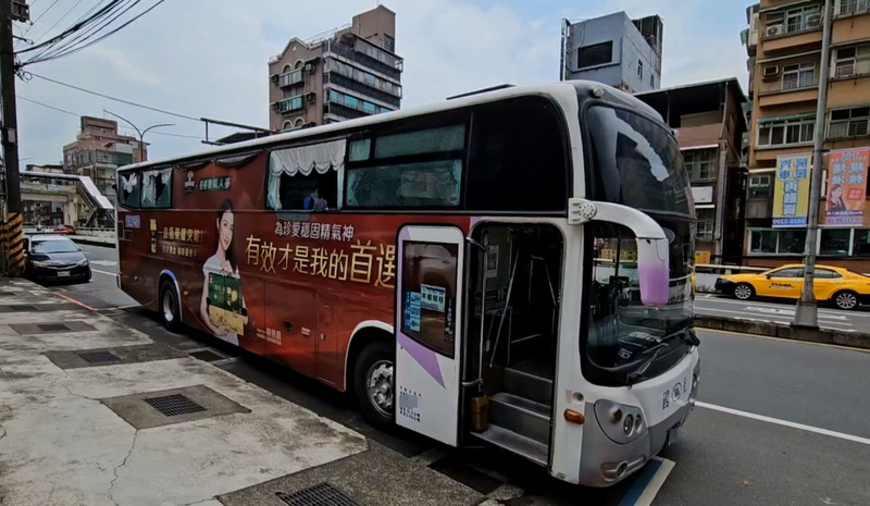 客運在窄巷中擦撞遮雨棚架，右側車窗也因此碎裂。圖/中央社