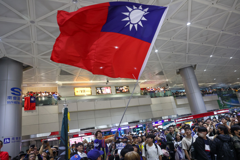 台灣隊奪下世界12強棒球賽冠軍，25日晚間球員搭機返台，桃園國際機場湧入大批球迷，球迷在現場揮舞大國旗。圖/中央社