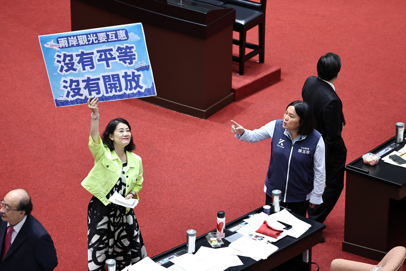 立法院會16日下午針對國民黨團提議解除「赴中觀光禁團令」等案進行表決。民進黨立委吳思瑤（綠衣者）高舉手牌，與國民黨立委陳玉珍（前右）在議場內互相表達立場。圖/中央社