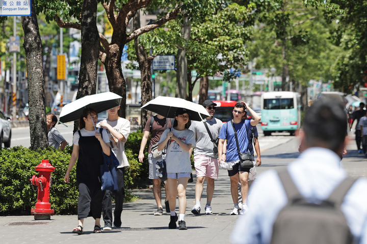 天氣晴朗炎熱，路上行人撐傘遮蔭。圖/取自中央社