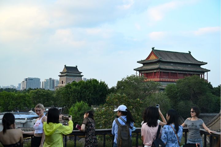 遊客在北京什刹海景區一戶外咖啡廳露台打卡鐘鼓樓。 圖/中新社記者 田雨昊 