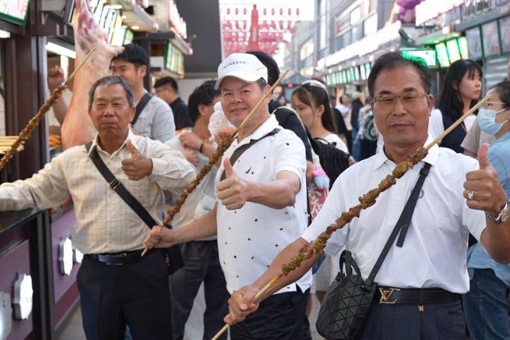 一串羊肉串長達1公尺，香噴噴的氣味，讓台灣阿伯們一人一串津津有味地吃著，還說：「讚！讚！讚！」。圖/記者陳思豪攝