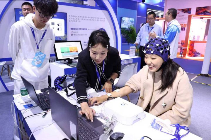 2025年10月17日，參觀者在HICOOL 2025全球創業者峰會上體驗高性能腦機介面控制下的軟體手部外骨骼聯合功能性電刺激設備。圖/中新社發  陳曉根 攝